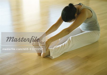 Yoga class, woman doing seated forward bend