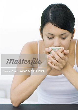 Woman holding up cup to face, eyes closed