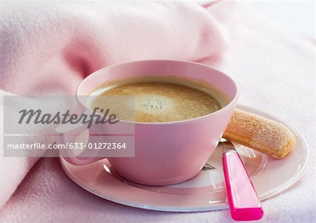 Cup of coffee on saucer with spoon and ladyfinger cookie