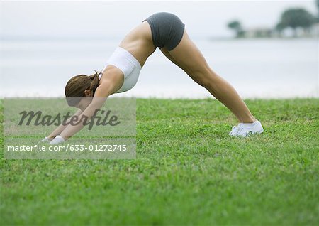 Young woman doing stretching exercises by lakeside