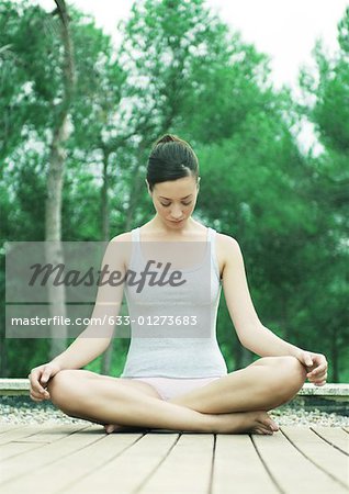 Woman sitting on deck in indian style, head down