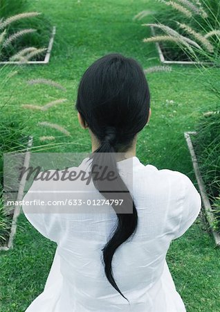 Woman sitting in ornamental garden, rear view