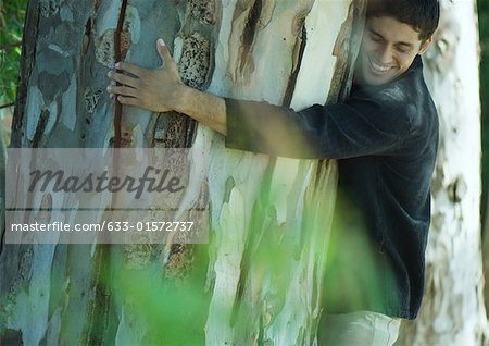 Man hugging tree, smiling, eyes closed