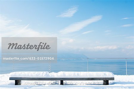 Snow-covered bench overlooking lake