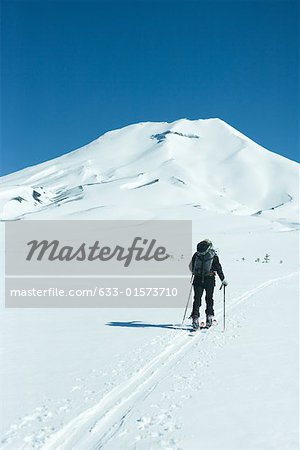 Skier heading toward mountain, rear view