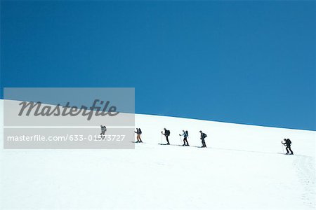 Skiers going up snowy slope, single file