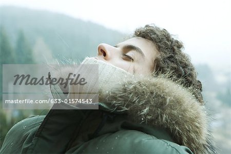 Teen boy standing outside with head back and eyes closed, mountain in background