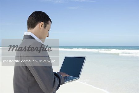 Businessman standing on beach, using laZSop