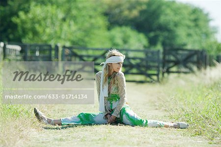 Young woman doing splits in rural field