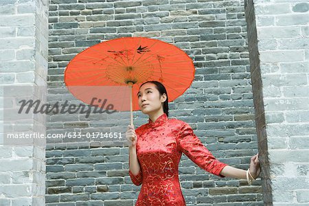 Young woman wearing traditional Chinese clothing, standing with parasol, waist up