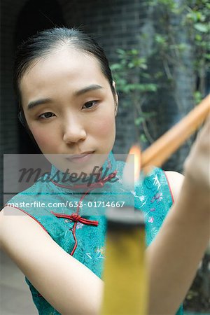 Young woman wearing traditional Chinese clothing, lighting incense