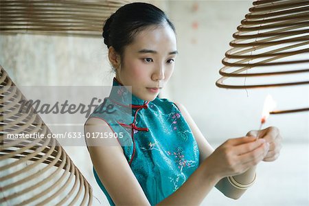 Young woman dressed in traditional Chinese clothing lighting spiral incense