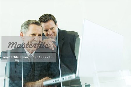 Two businessmen looking at laZSop computer together, both smiling, low angle view