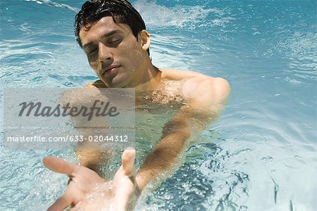 Man in swimming pool, eyes closed, arms outstretched