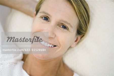 Woman lying on back, smiling at camera, high angle view