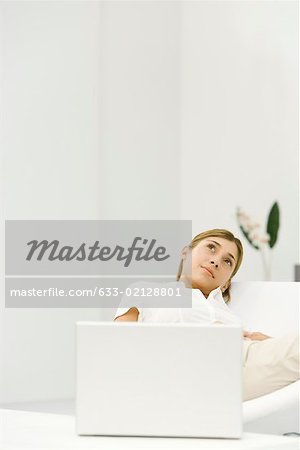 Woman reclining in chair beside laZSop computer, looking up, smiling