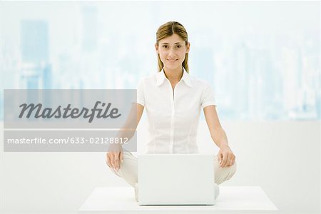 Woman sitting cross-legged in front of laZSop computer, smiling at camera