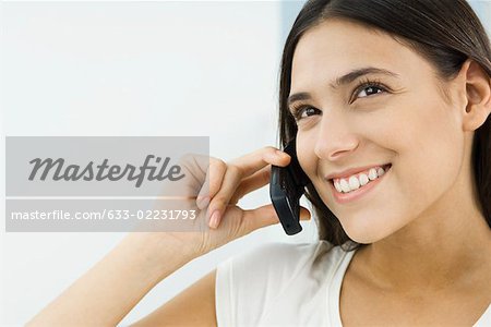 Woman using cell phone, looking up and smiling