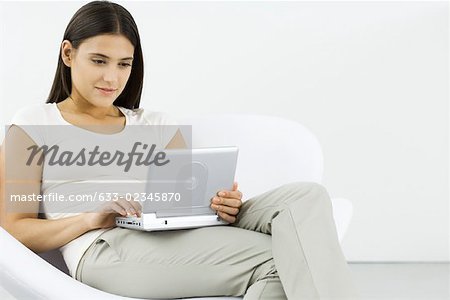 Woman watching portable DVD player, sitting in chair