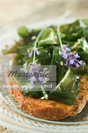 Toast topped with seaweed and sesame seeds, garnished with lavender flowers