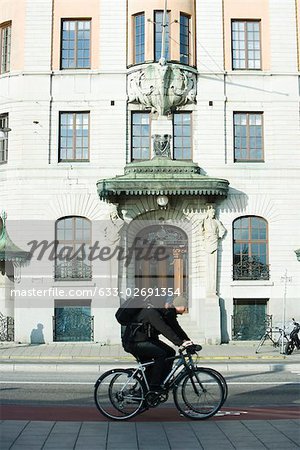 Sweden, Stockholm, bicyclists riding past ornate building