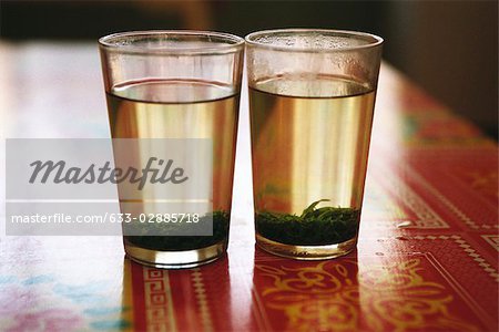Two glasses of tea with tea leaves steeping