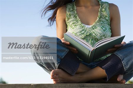 Woman reading book outdoors, cropped