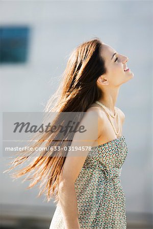 Young woman walking outdoors, long hair tousled by wind