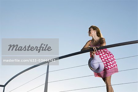 Woman leaning against balcony railing, looking at view