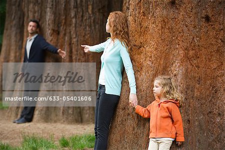 Parents leaning against separate trees, reaching out for each other