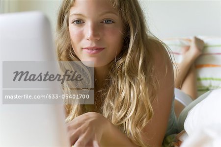 Young woman lying in bed, using laZSop computer