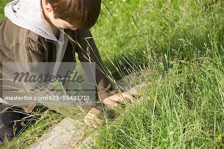 Boy down on all fours, investigating something on the ground