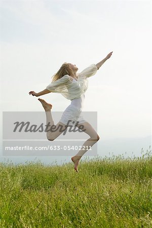 Young woman jumping in midair, side view