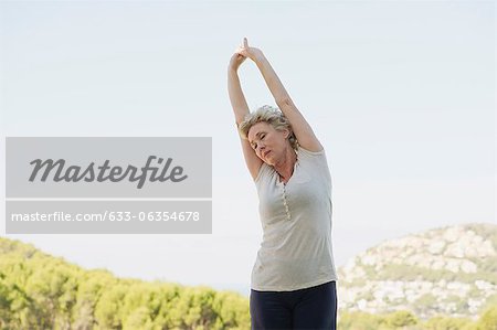 Mature woman stretching arms