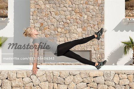 Young woman doing pilates exercise outdoors, eyes closed, side view