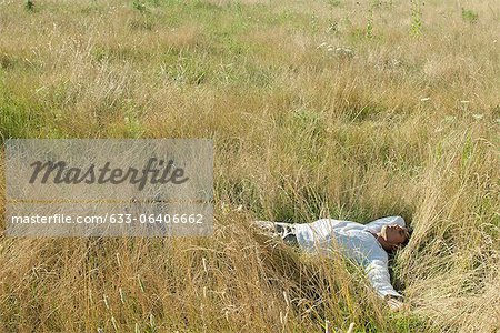 Mid-adult man relaxing in field with eyes closed