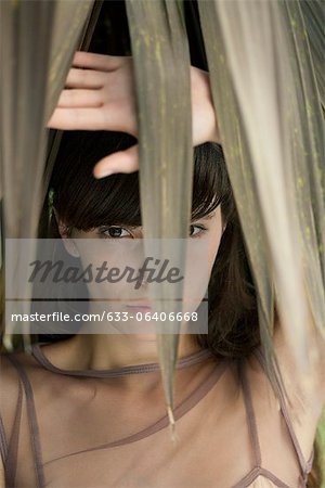 Young woman behind tropical foliage, portrait