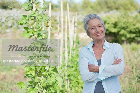 Senior woman smiling proudly in vegetable garden