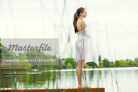 Woman standing at end of lake pier enjoying view