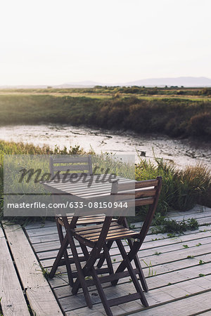 Wooden table and chairs on deck in tranquil scene