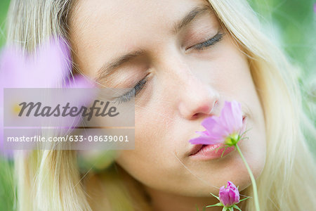 Young woman smelling flowers with eyes closed, portrait