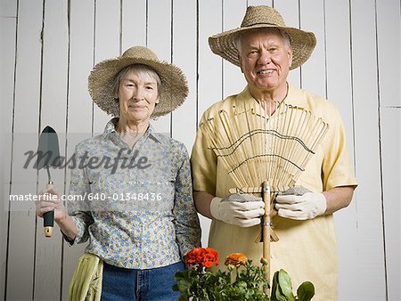 Portrait of an elderly couple standing with gardening tools