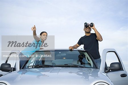 Young man and a young woman standing near a car