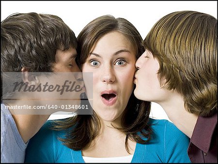 Two boys kissing girl on cheeks