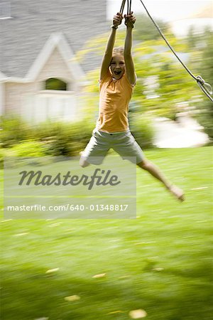 Low angle view of a girl swinging from a rope