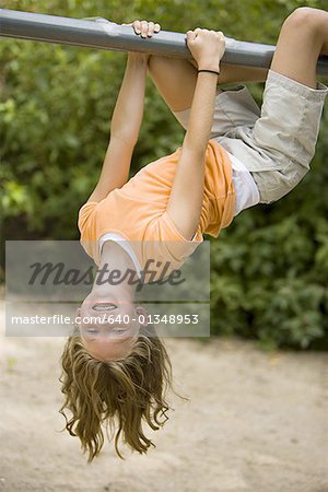 Portrait of a girl hanging upside down from a jungle gym