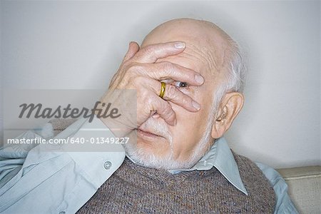 Portrait of a senior man looking through his fingers