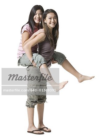 Teenage girl giving friend piggyback ride Stock Photo - Alamy