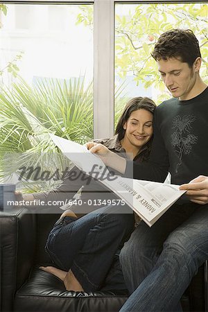 Close-up of an adult couple reading a newspaper