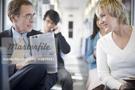 Businessman and a businesswoman talking on a commuter train Businessman and a businesswoman talking on a commuter train